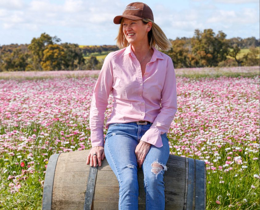A lady sitting on a barrel in a field of everlastings